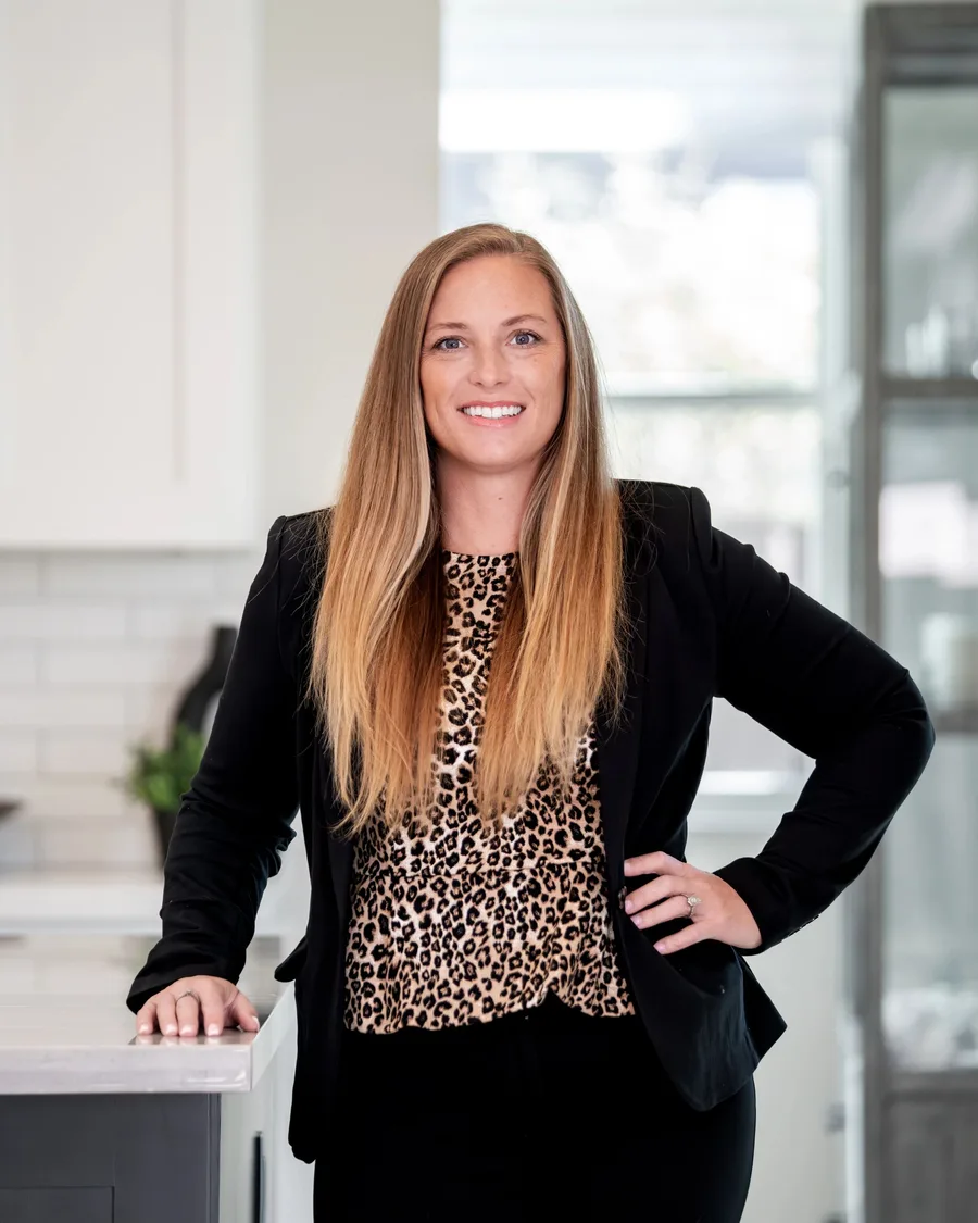 The owner of Prestige Desert Cleaning Co in a black blazer and leopard print top, smiling in a kitchen